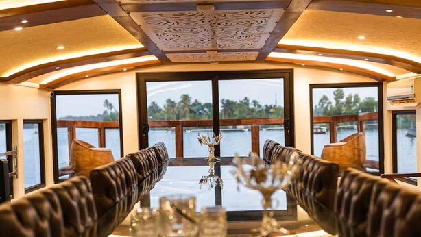 A dining area with a view of the water, featuring leather seating and a glass table.