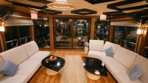 A modern interior with two white sofas, a central black coffee table, and a chandelier.