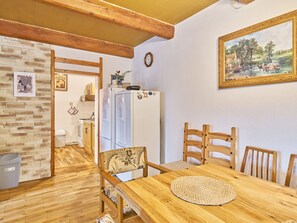 A warm and inviting space with a dining table, refrigerator, and a serene landscape painting.