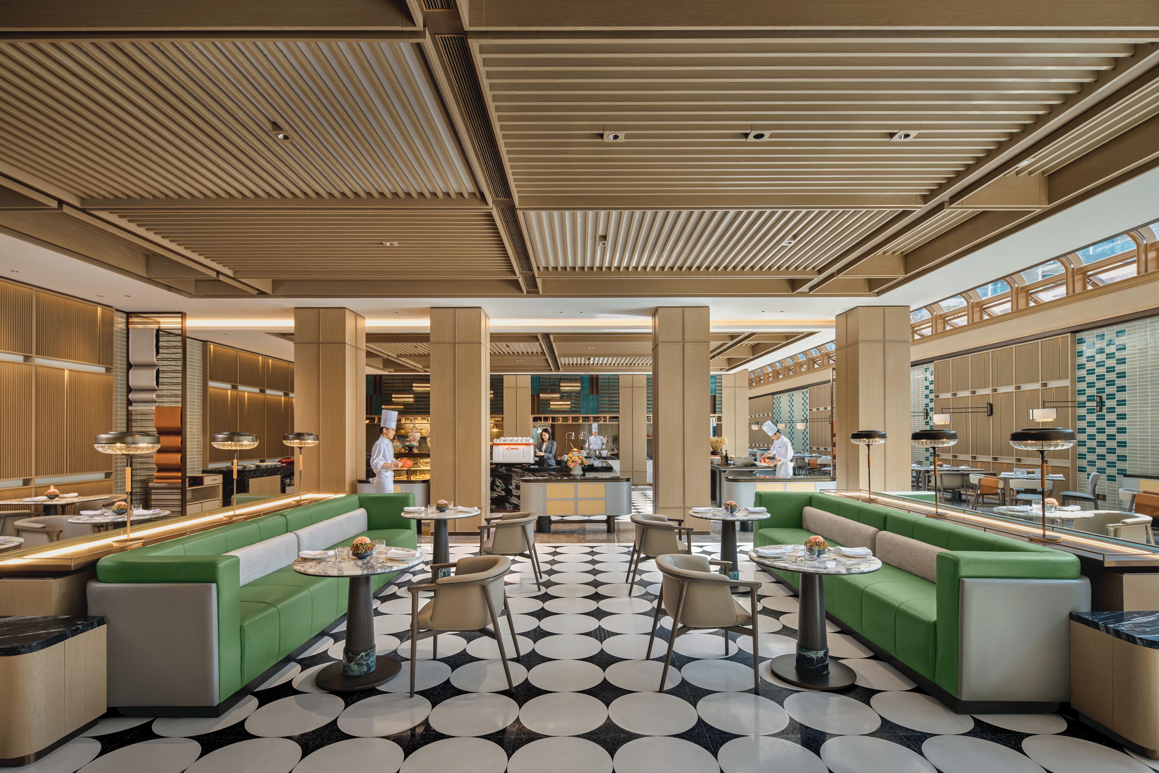 A spacious lobby with green seating areas, a central bar, and a patterned floor.