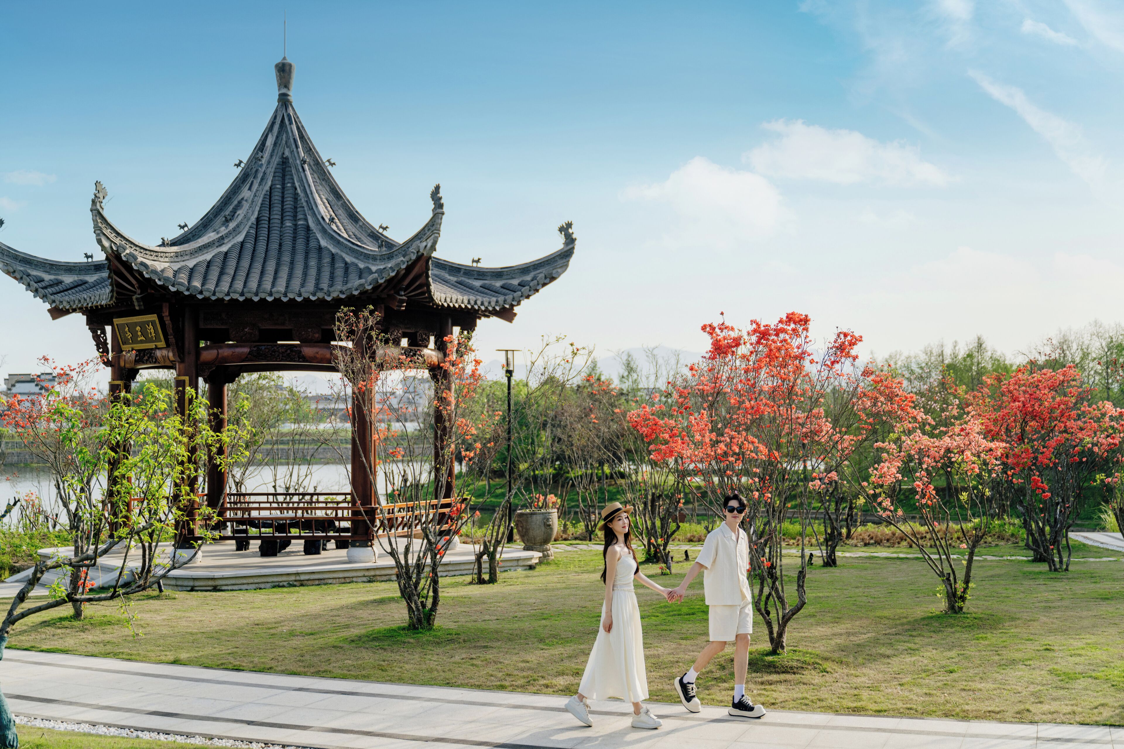 A traditional pavilion with a curved roof, a bench, and a pathway leading to it.