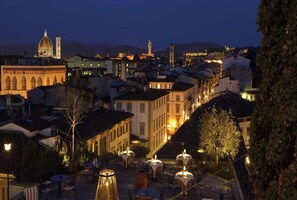 A cityscape at dusk with illuminated buildings, a prominent dome, and a tower. - Charming Apartment with Rooftop Terrace and Panoramic Views near Ponte Vecchio (Firenze)