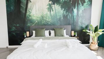 Une chambre à coucher moderne avec un grand lit, une fresque murale sur le thème de la forêt, une table de chevet avec une lampe et une plante en pot.