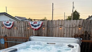 Un jacuzzi con panel de control, rodeado por una terraza de madera y una valla de madera.