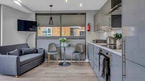 A modern kitchen with grey cabinets, a built-in oven, and a dining area with a grey sofa and two chairs.