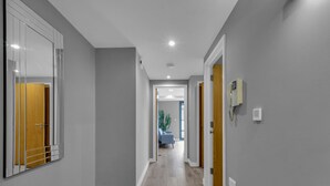 A hallway with grey walls, wooden flooring, and a blue sofa in the distance.