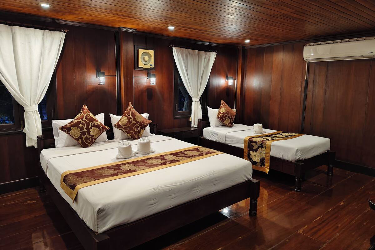 A hotel room with two beds, wooden flooring, and a wooden ceiling.