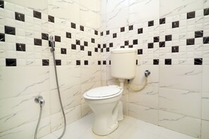 Un baño con inodoro, ducha y paredes de azulejos.