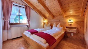 Une chambre de style cabane en bois avec deux lits, une fenêtre avec des rideaux, un radiateur et des lampes fixées au mur.