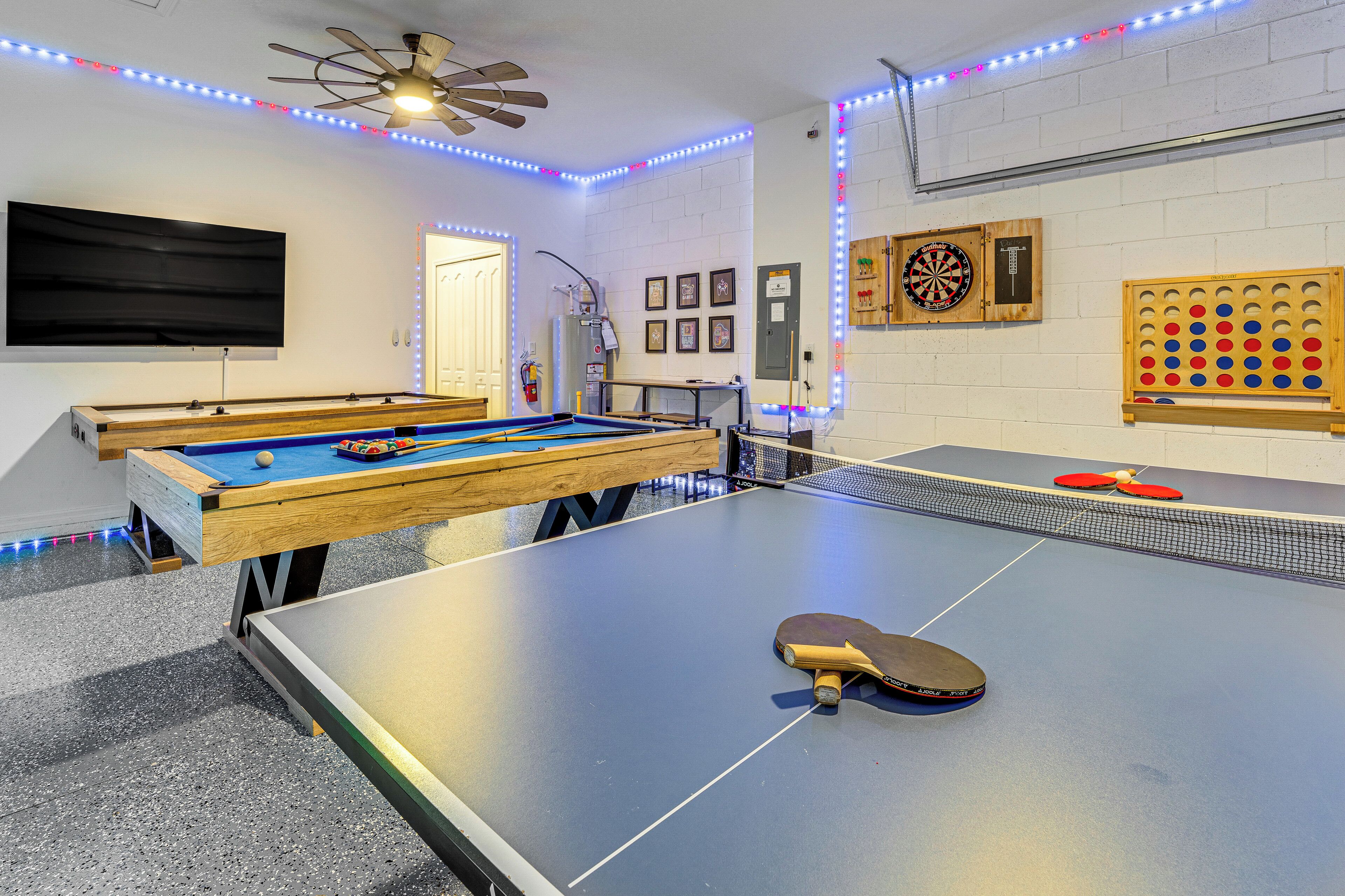 Une salle de loisirs équipée d’une table de billard, d’une table de ping-pong et de cibles de fléchettes.