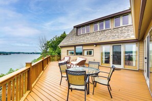 A deck with a table and chairs overlooking a body of water.