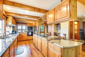 A spacious kitchen with wooden cabinets, granite countertops, and a large island.