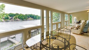 Ein geräumiges Zimmer mit großem Fenster mit Blick auf einen Fluss, einem runden Glastisch mit Stühlen und einer Sitzecke mit Sofa und Sesseln.