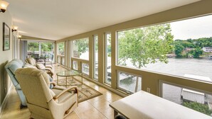 Ein geräumiger Balkon mit Blick auf einen Fluss und Bäume, eine gemütliche Sitzecke mit einem Glastisch und Wasserblick.