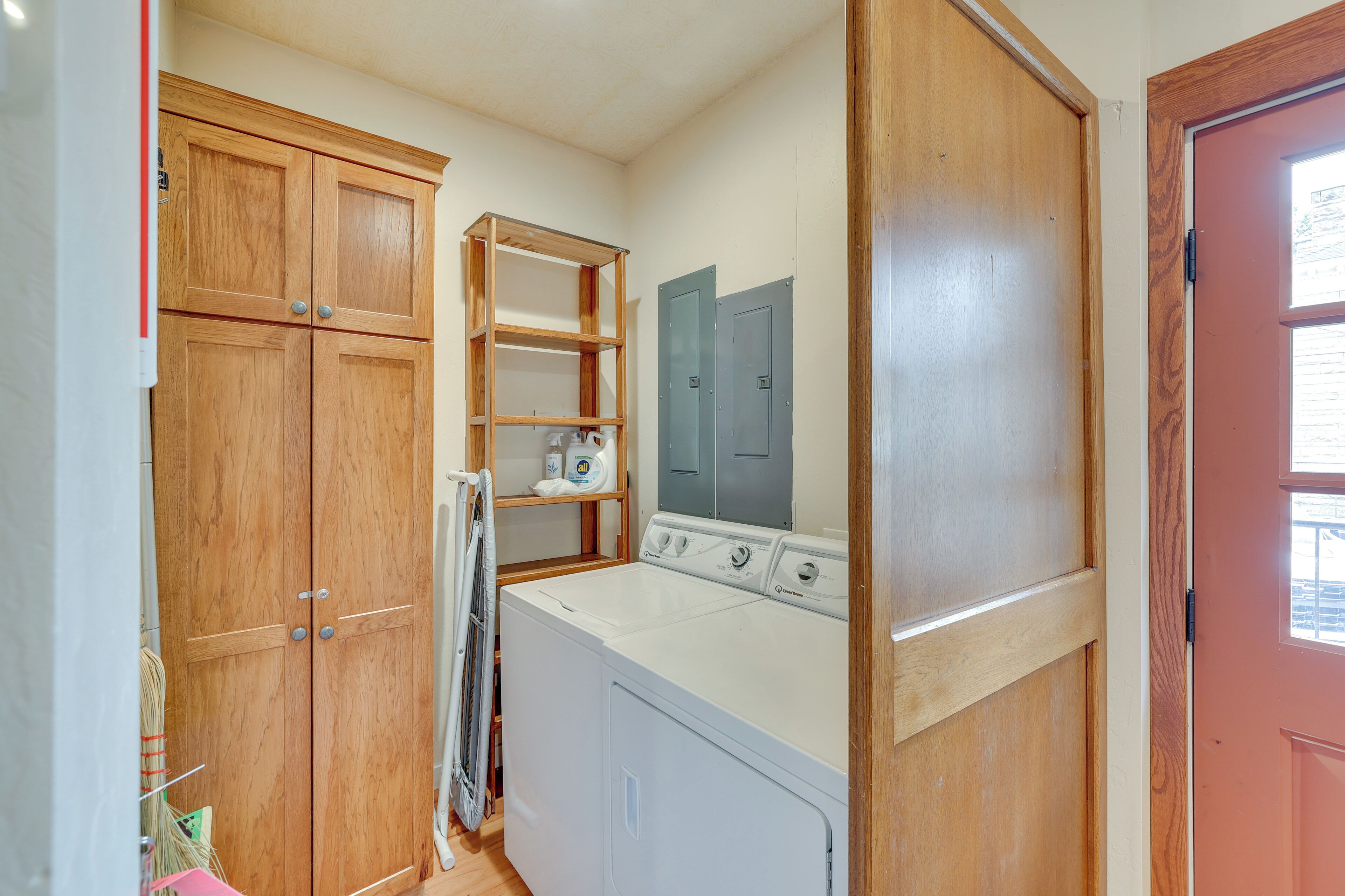 Un cuarto de lavado con gabinetes de madera, una lavadora y un estante con productos de lavandería.