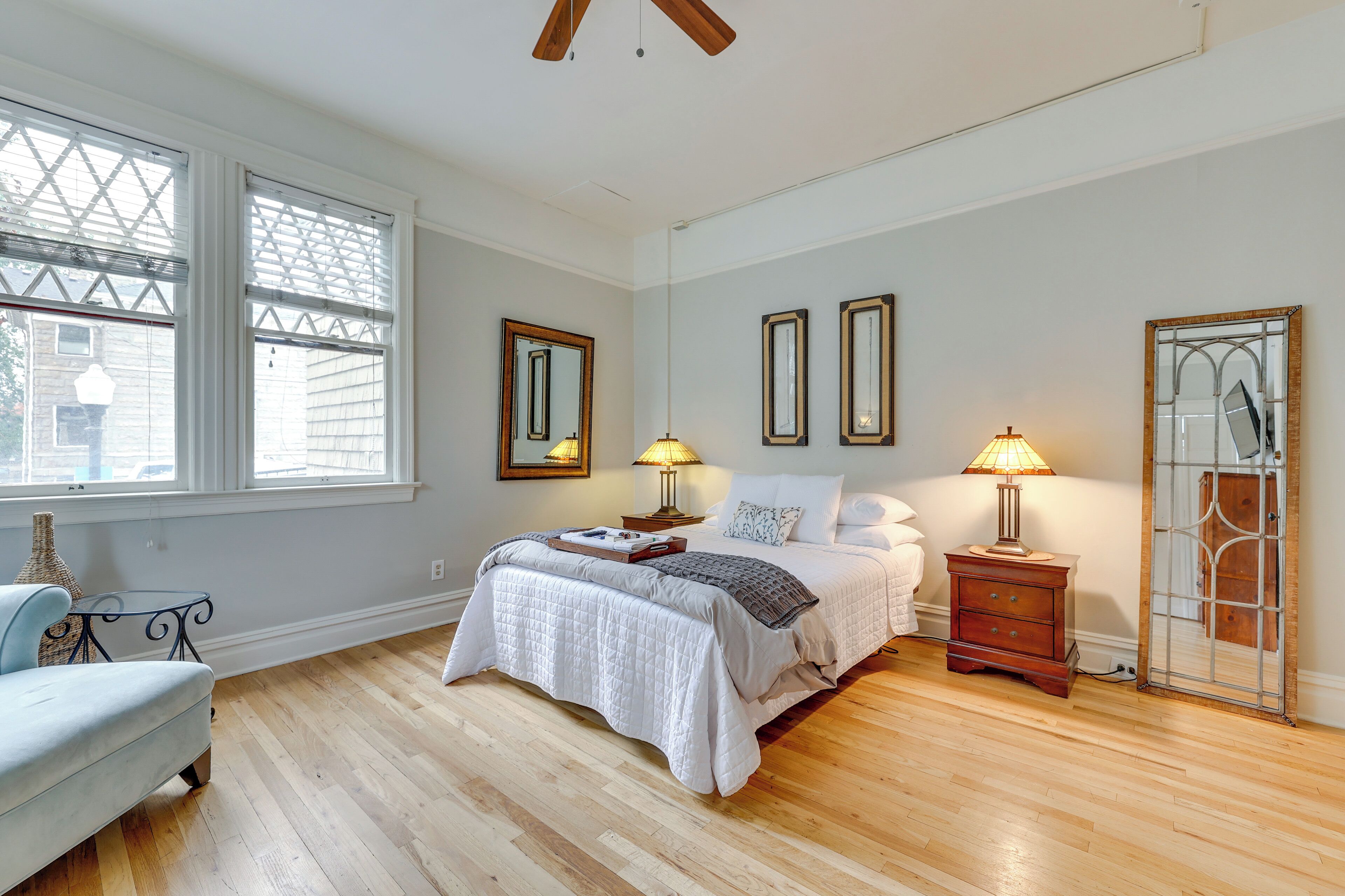 A bedroom with a bed, bedside tables, lamps, and a large window.