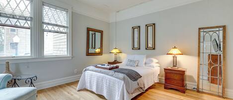 A bedroom with a bed, bedside tables, lamps, and a large window.