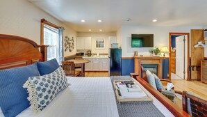 A hotel room with a bed, a desk, a chair, a sofa, a fireplace, a TV, and a kitchen area. - Historic Boise Studio w/ Courtyard, Blocks to Dtwn (Boise)