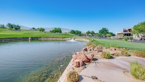 Un paysage paisible avec un étang, un terrain de golf et un bâtiment moderne.