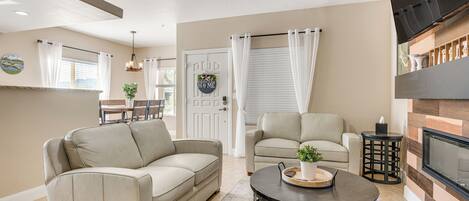 A living room with two beige sofas, a coffee table, a fireplace, and a ceiling fan.