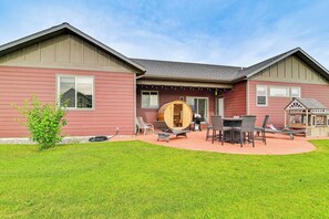 A two-story house with a patio area featuring outdoor furniture and a wooden barrel. - Belgrade Studio w/ Mountain Views: Near Bozeman! (Belgrade)