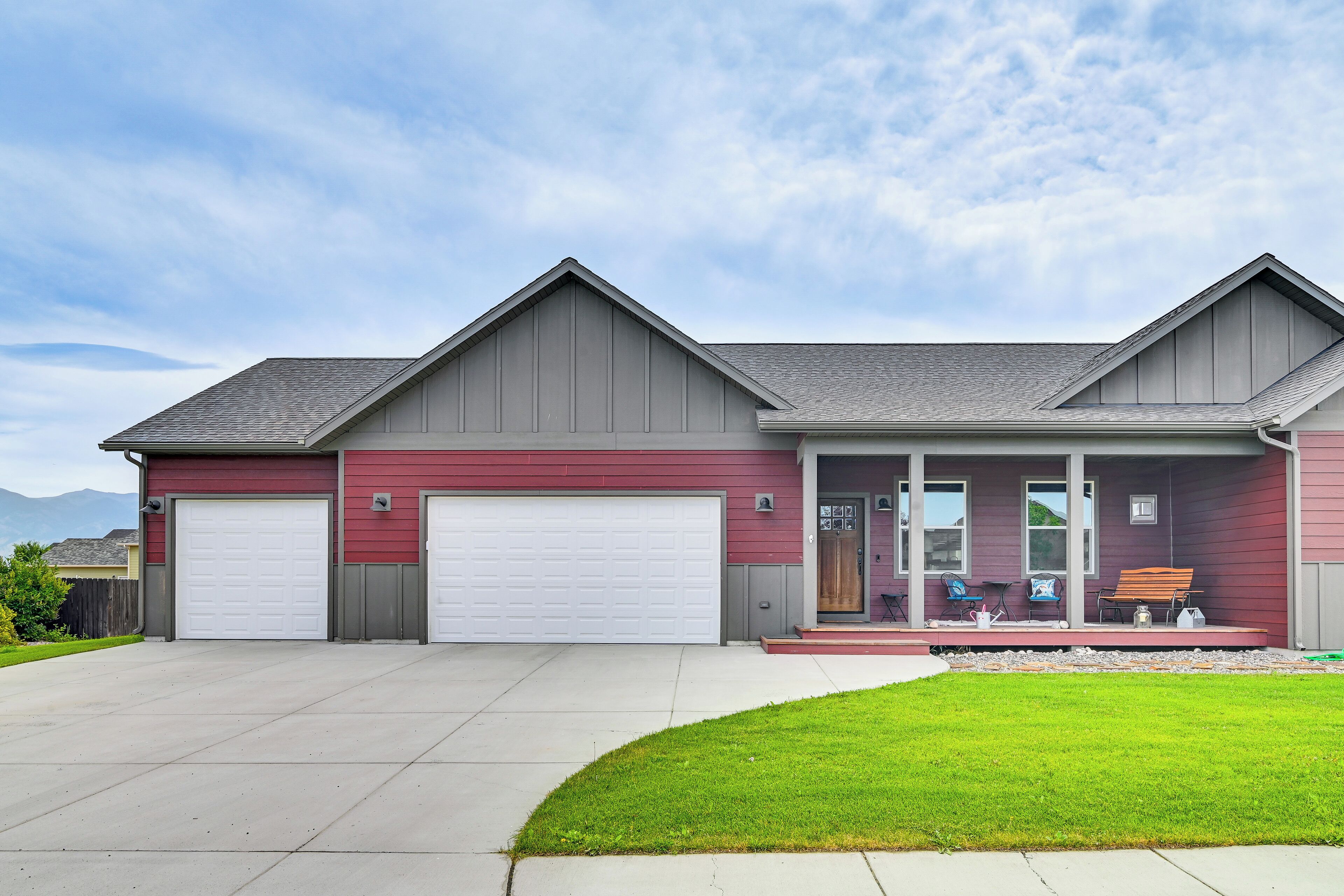 A two-story house with a garage, a covered porch, and a well-maintained lawn.