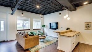 Een moderne woonkamer met een bank, stoelen, een salontafel en een keukeneiland.