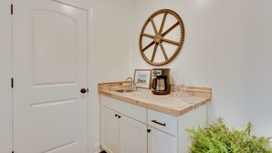 Een keuken met een houten aanrecht, een koffiezetapparaat, een spoelbak en een decoratieve wiel aan de muur.