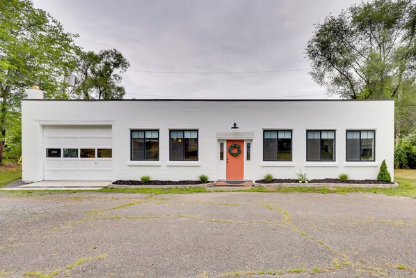 Een modern eenlaags huis met garage, een veranda en een rode deur.