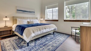 Een slaapkamer met een bed, nachtkastjes, een grote raam en een plafondventilator.