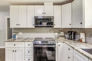 A kitchen with white cabinets, a stainless steel microwave, a Samsung oven, and a granite countertop. - 1 Mi to Ocean Isle Beach Pier! Family Home w/ Yard (Ocean Isle Beach)