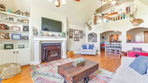 A spacious living room with a fireplace, a television, and a dining area. - Fire Pit + Sauna: Spacious Lake Texoma Retreat! (Denison)