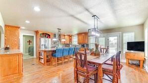 A spacious kitchen with wooden cabinets, a central island, and a dining area with chairs and a table. - Fire Pit + Sauna: Spacious Lake Texoma Retreat! (Denison)