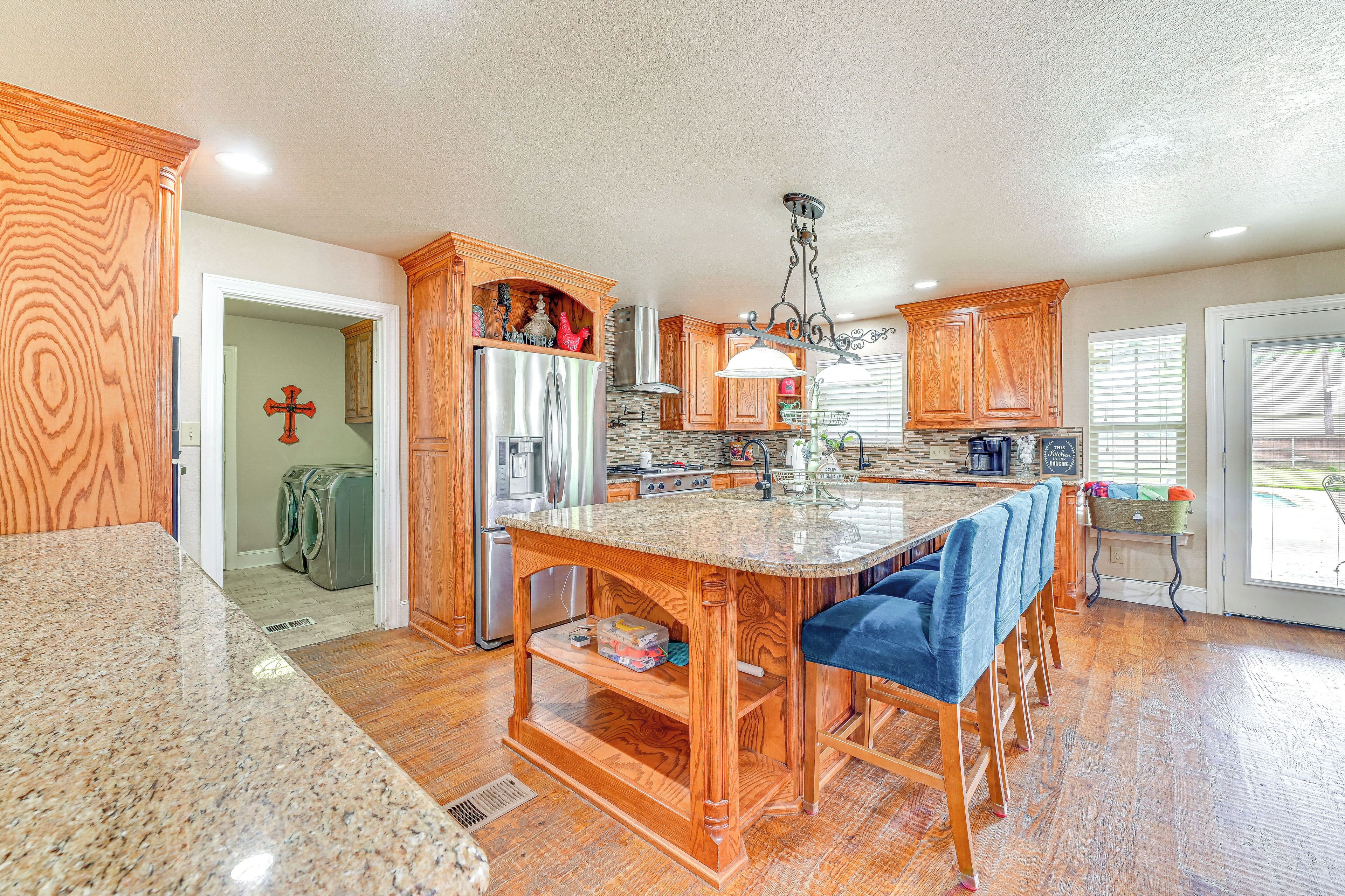 A kitchen with wooden cabinets, granite countertops, and a central island with bar stools.