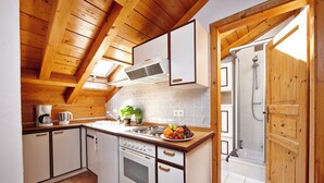 Une cuisine avec des poutres en bois, des armoires blanches, une cuisinière et un évier.