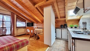 Un chalet confortable avec un intérieur en bois, un coin repas, une kitchenette et un téléviseur.