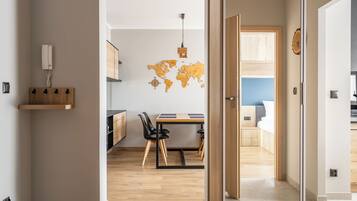 A modern kitchen with a wooden table and chairs, a world map wall decoration, and a hanging light fixture.