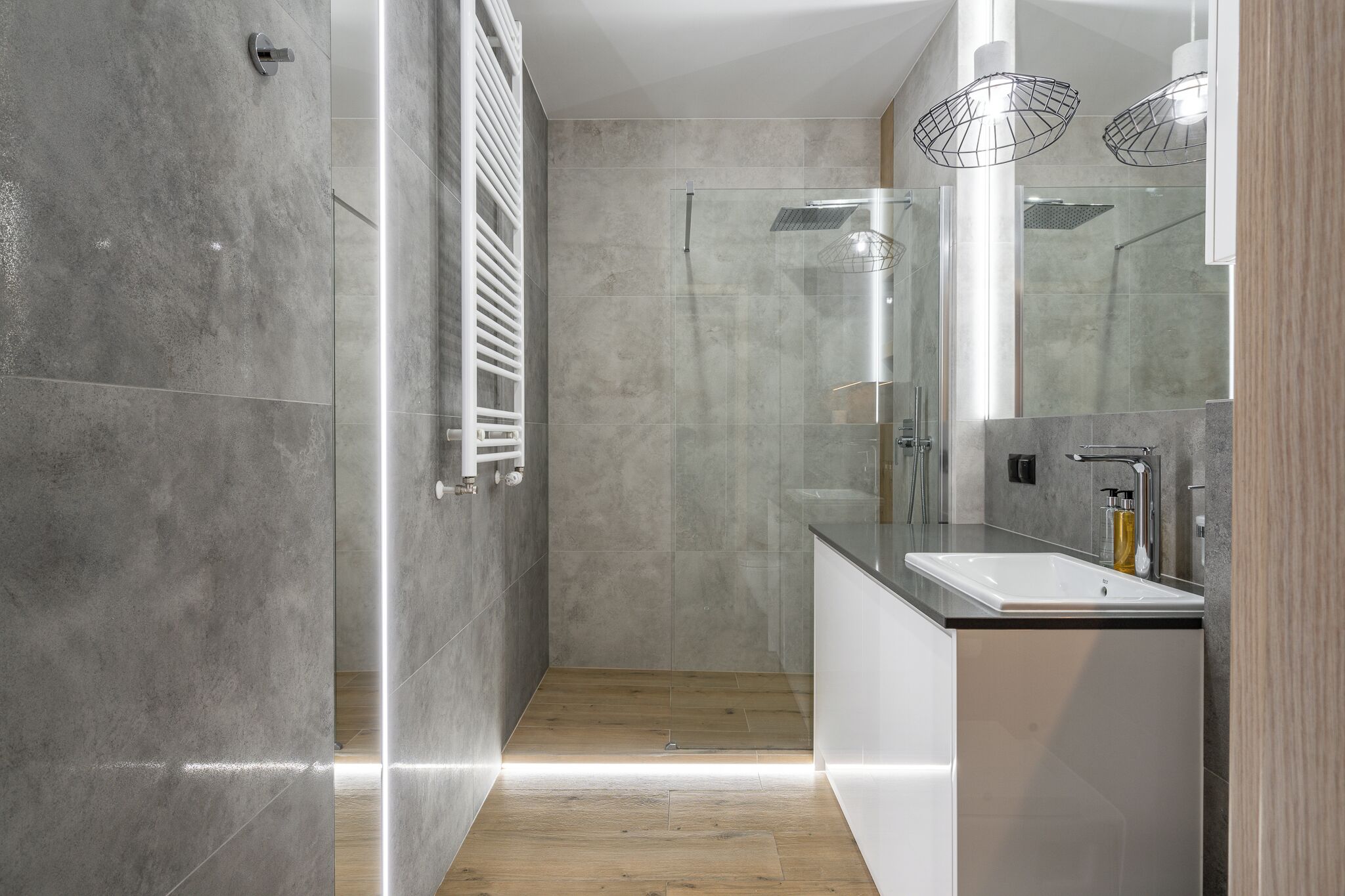 A modern bathroom with a glass-enclosed shower, a white sink, and a large mirror.