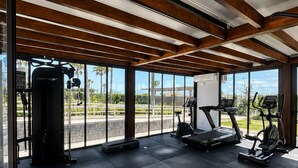 Ett gym med träningsutrustning, stora fönster och utsikt över omgivningarna.