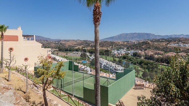 A view of a residential area with a sports court, palm trees, and distant mountains. - RDR417 - Renovated townhouse walk to beach and golf (La Cala de Mijas)
