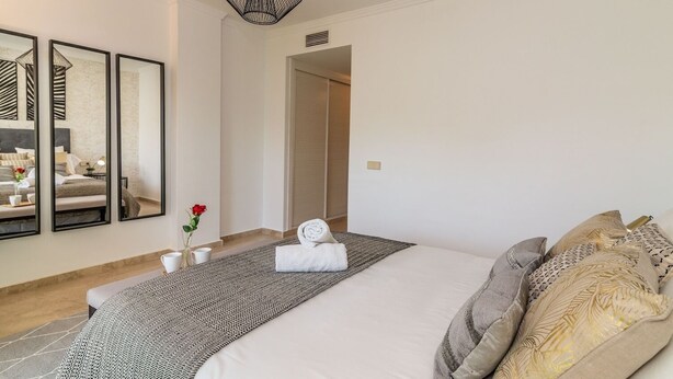 A modern bedroom with a large bed, a bedside table with a vase of flowers, and a unique geometric pendant light. - RDR473 - Excellent Banús with pool and parking (Marbella)