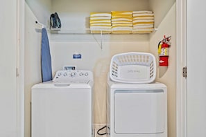 - Washer and dryer set with a clean and organized layout - Shelving above the machines stocked with neatly folded yellow and white towels - Essential laundry items like an iron, ironing board, and laundry basket within reach - Disney near Resort 9BR Home Oasis w/ Pool (Kissimmee)