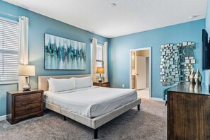 A bedroom with a bed, nightstands, a dresser, and artwork on the walls.