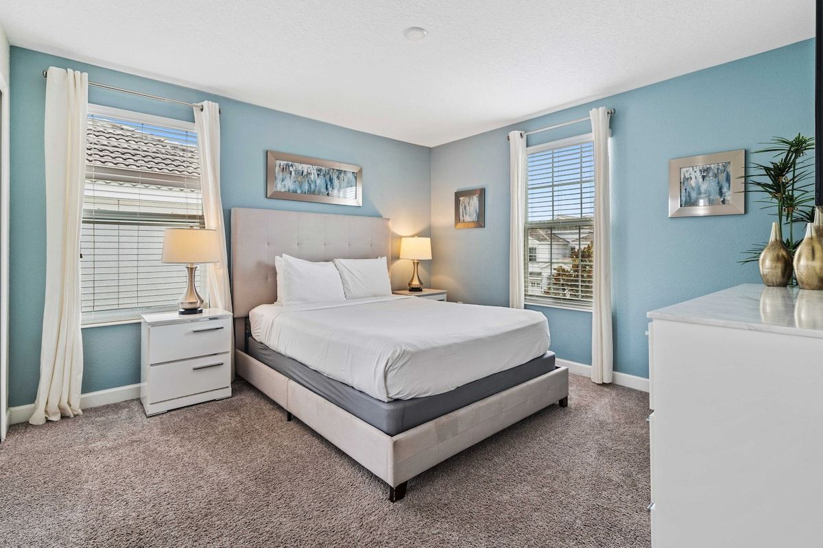 A bedroom with a bed, bedside tables, and artwork on the walls.