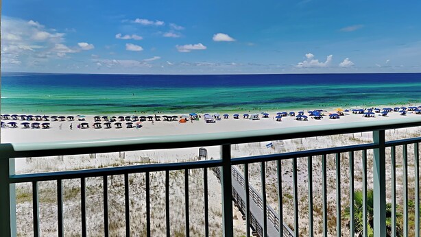 A beach view with a railing, clear sky, and ocean. - Pelican Isle #513 | Seasonal Beach Service + Resort Amenities (Fort Walton Beach)