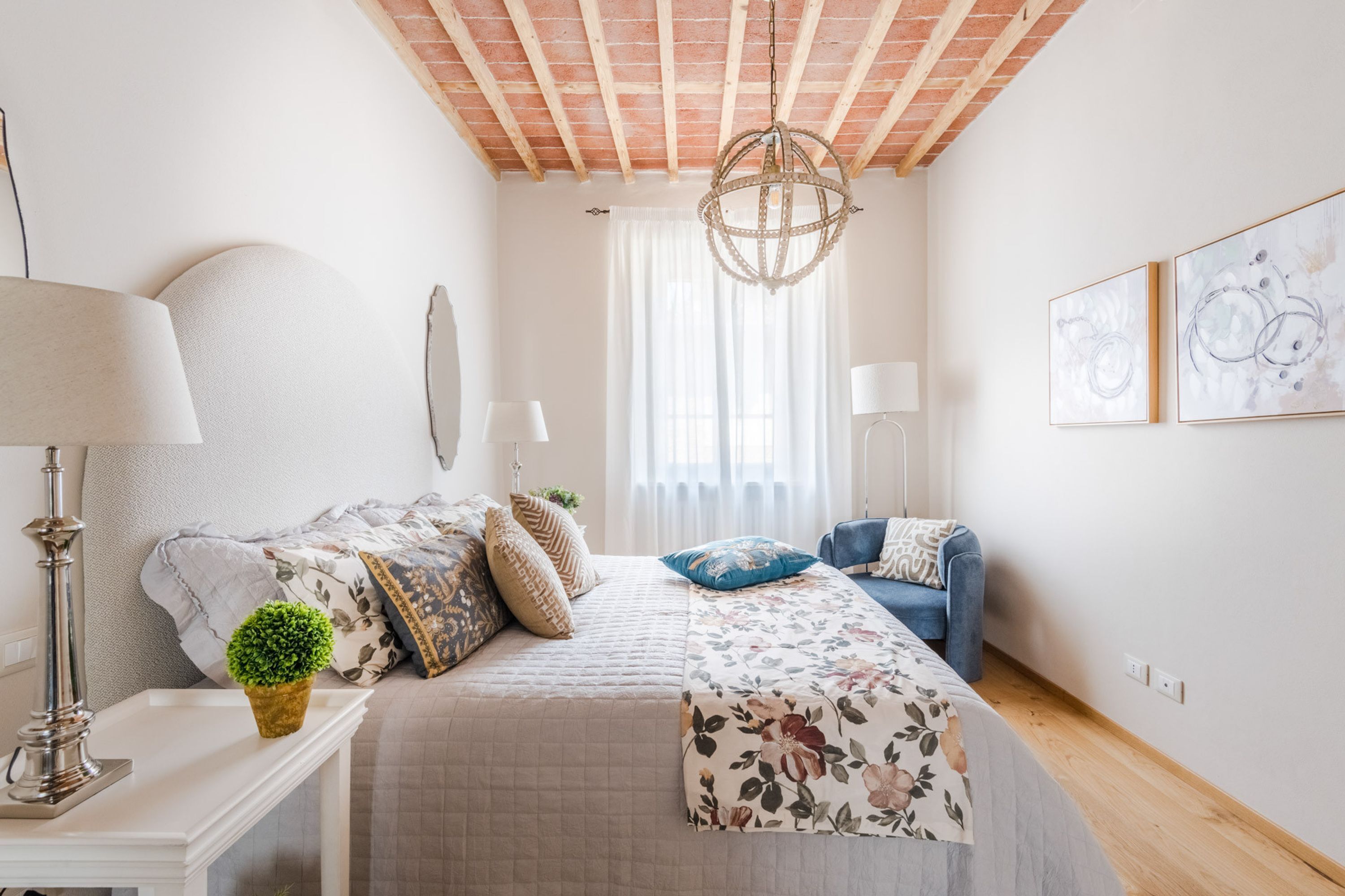 A bedroom with a bed, bedside table, lamp, and a small plant.
