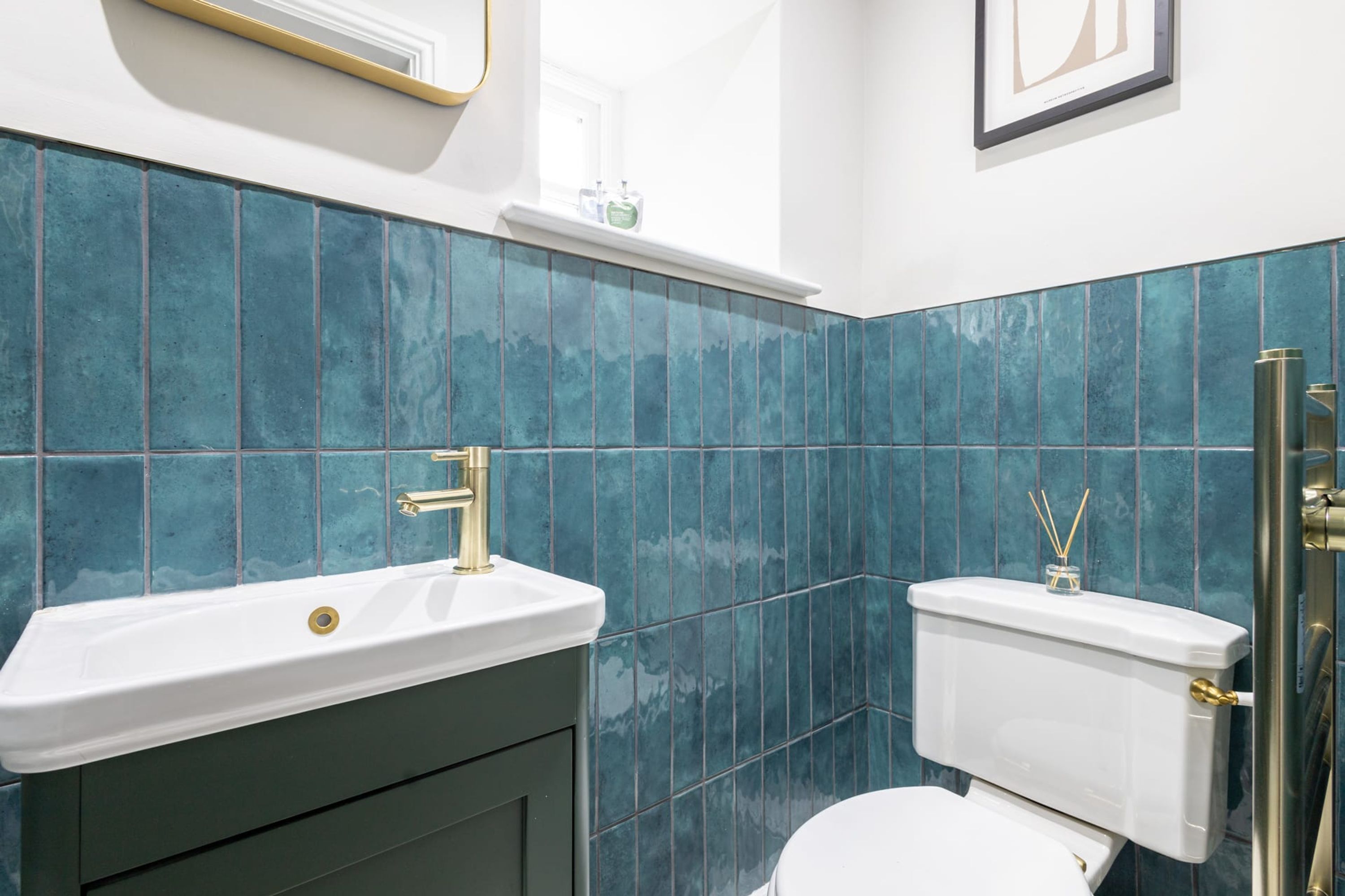 Un baño con un lavabo blanco, inodoro y azulejos verde azulado.