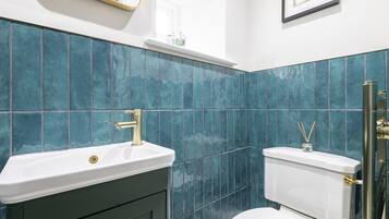 Un baño con un lavabo blanco, inodoro y azulejos verde azulado.