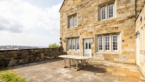 Ein Steinhaus mit einer Terrassenfläche, komplett mit Tisch und Stühlen.