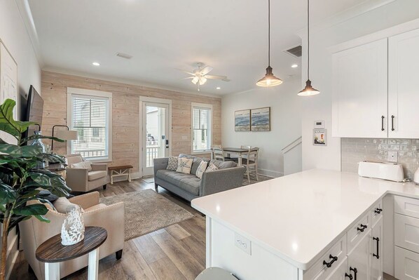 A modern kitchen with white cabinets, a large island, and pendant lighting.